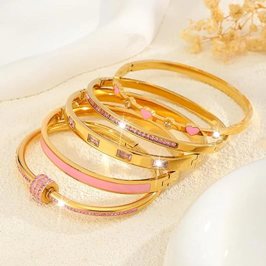 MyClosetAid stackable gold bangle bracelet set with pink accents and heart details on beige background